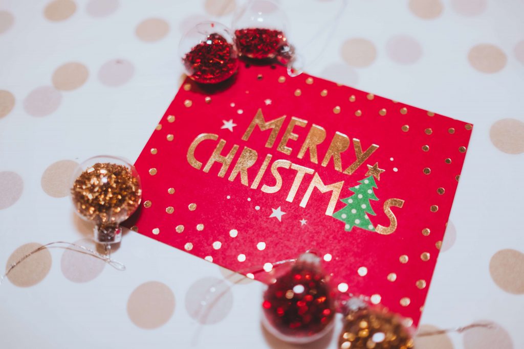 A red card on a table saying Merry Christmas surrounded by baubles.