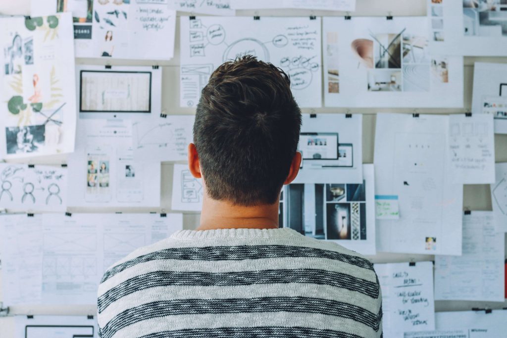 A man planning content on a large pin board