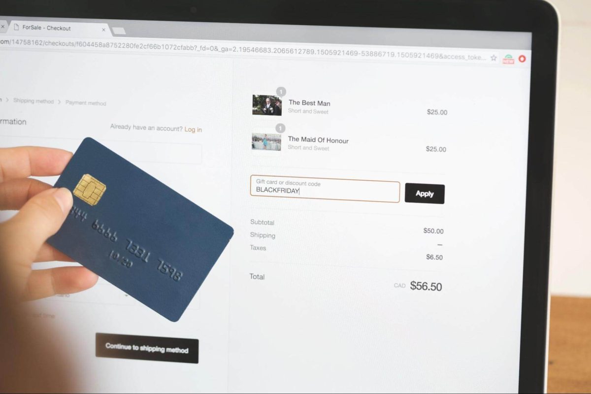 Someone holding a credit card and inputting a discount code into a checkout page.