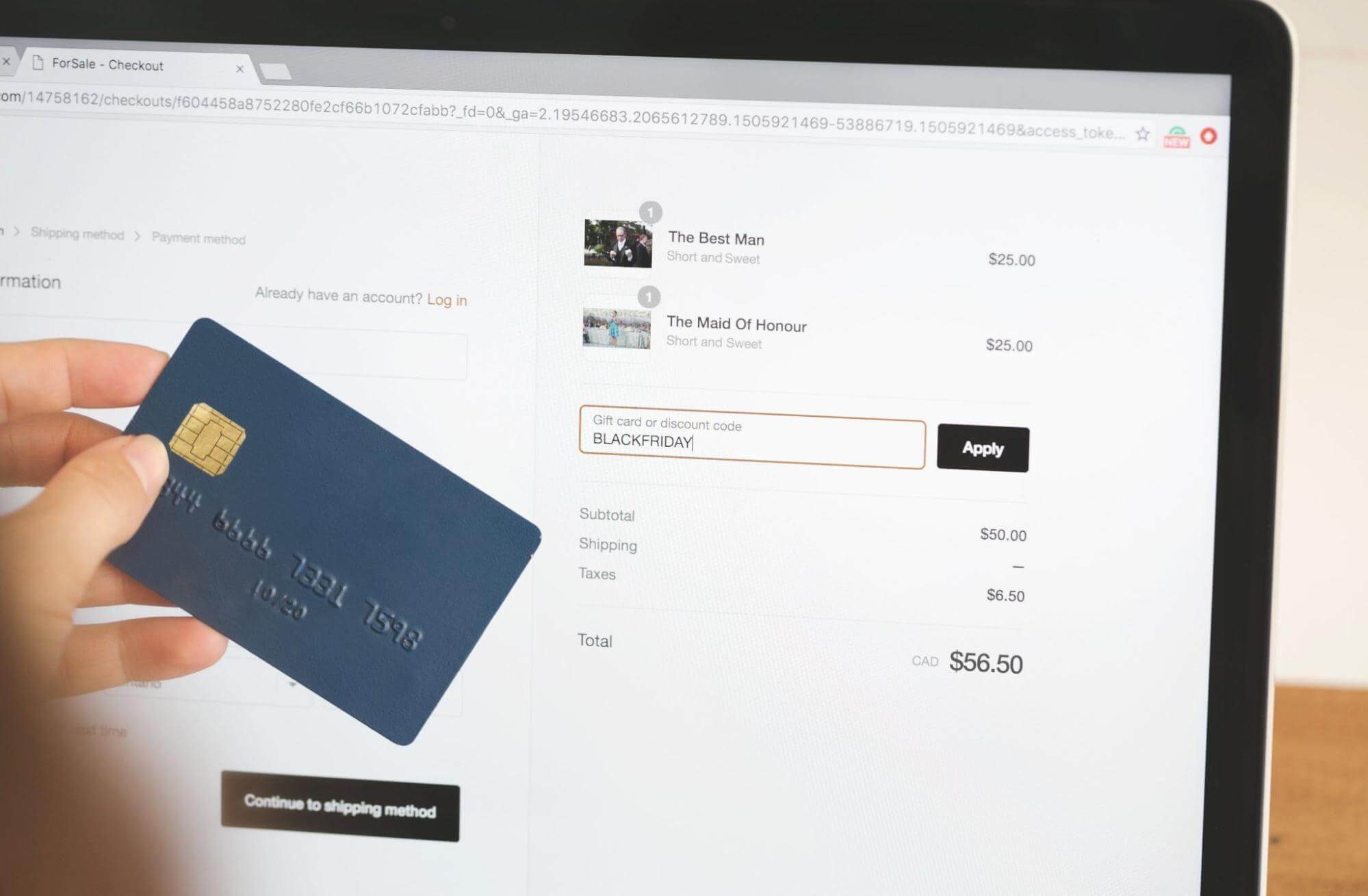 Someone holding a credit card and inputting a discount code into a checkout page.