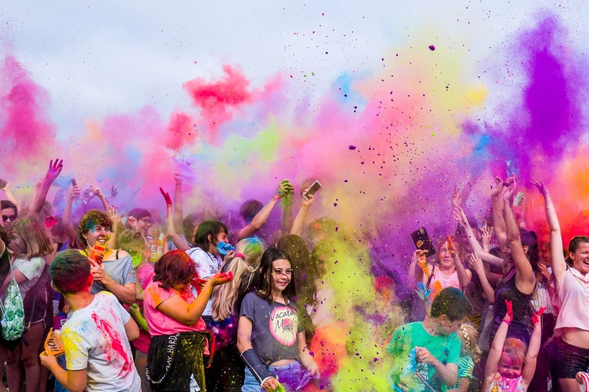 a group of people throwing colour powder in the air outside