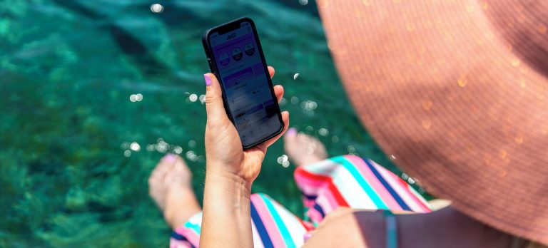 a woman holding her phone over a pool looking at the jet2 app