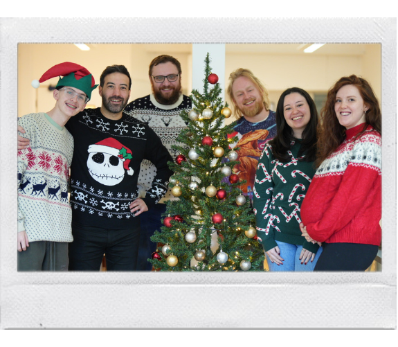 A polaroid frame of the wonder agency team in christmas jumpers around a christmas tree