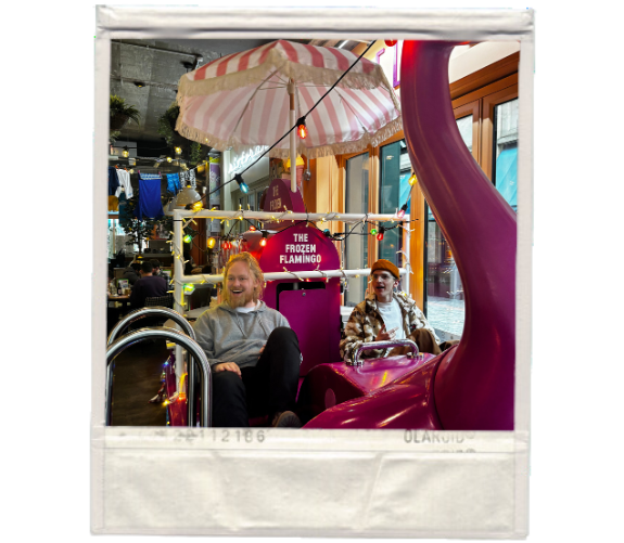 a polaroid frame of jacob and harry from the wonder agency in a flamingo boat