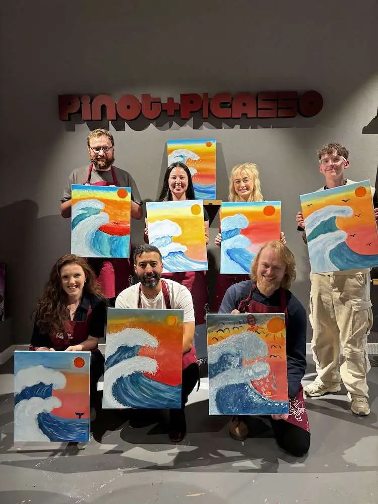 The Wonder Agency team holding up paintings at pinot and picasso