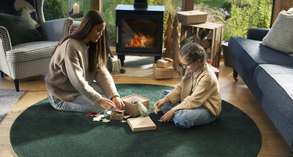 Two girls wrapping Christmas presents on a rug, featured on a case study on Wonder Agency's custom advent calendar build for Hug Rug